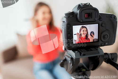 Image of woman with bronzer and camera recording video