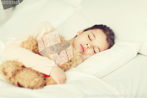 Image of girl sleeping with teddy bear toy in bed at home