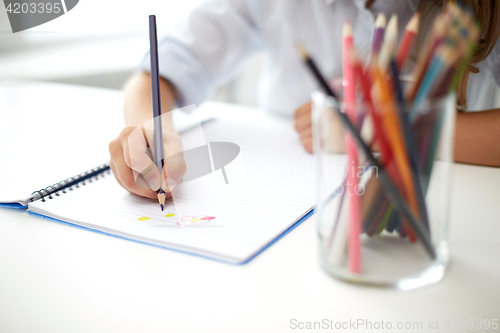 Image of girl drawing with color pencil pen in notebook