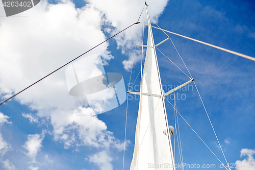 Image of white sail on mast of boat over blue sky