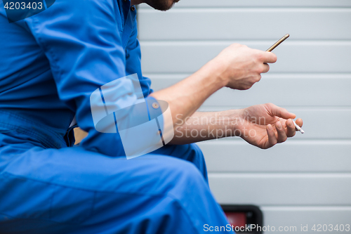 Image of auto mechanic smoking cigarette at car workshop