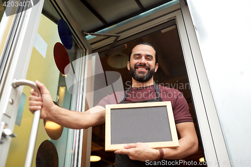 Image of man or waiter with blackboard at bar entrance door