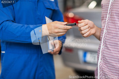 Image of auto mechanic giving car key to man at workshop