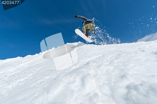 Image of Snowboarder jumping against blue sky