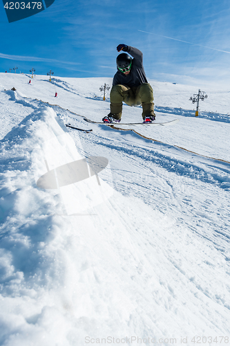 Image of Snowboarder jumping against blue sky