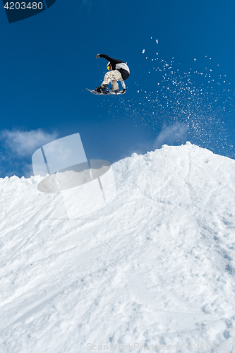 Image of Snowboarder jumping against blue sky