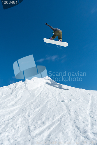 Image of Snowboarder jumping against blue sky