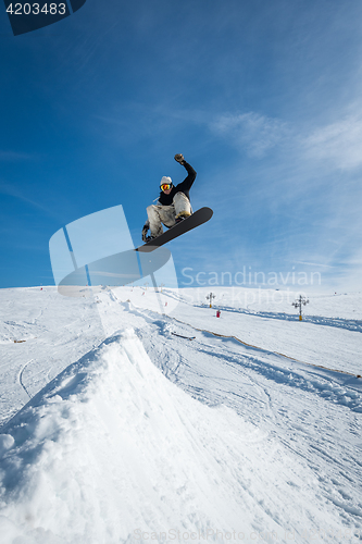 Image of Snowboarder jumping against blue sky