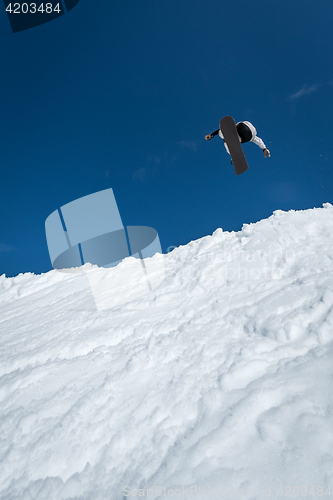 Image of Snowboarder jumping against blue sky