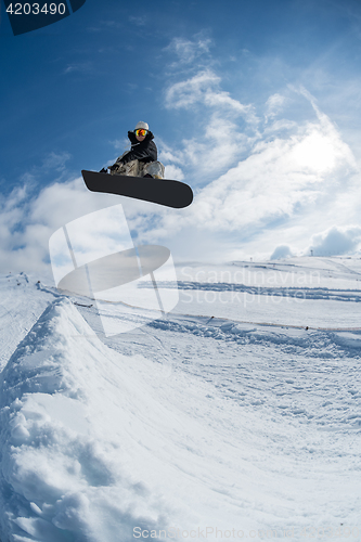 Image of Snowboarder jumping against blue sky