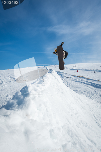 Image of Snowboarder jumping against blue sky