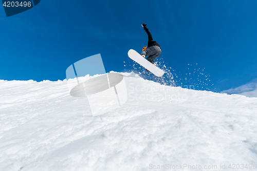 Image of Snowboarder jumping against blue sky