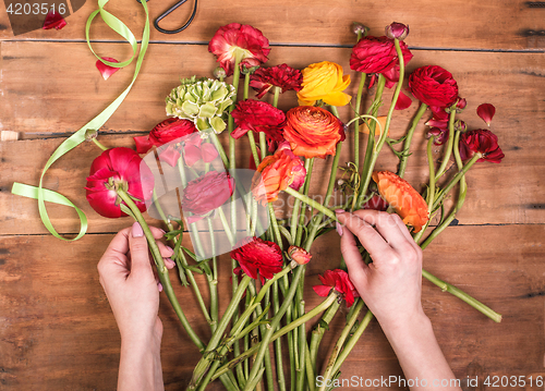 Image of Ranunkulyus bouquet of red flowers on a wooden background