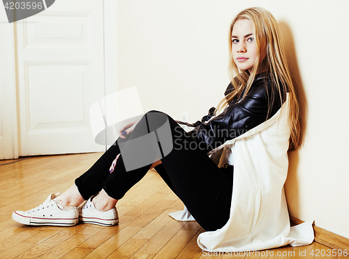 Image of young pretty teenage blond girl sitting on floor at home despair