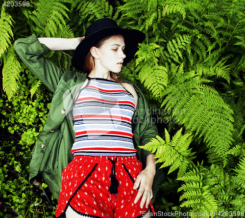 Image of Pretty young blond girl hipster in hat among fern, vacation in g