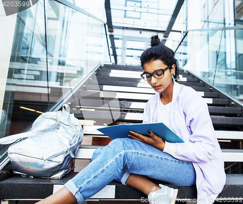 Image of young cute indian girl at university building sitting on stairs 