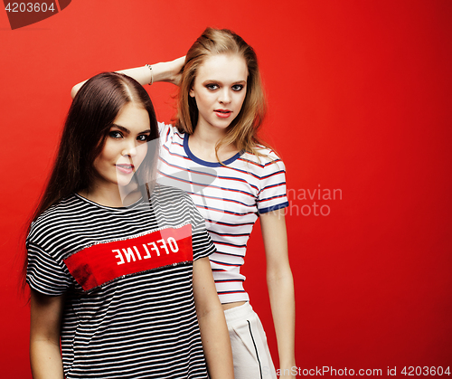 Image of two best friends teenage girls together having fun, posing emotional on red background, besties happy smiling, lifestyle people concept 