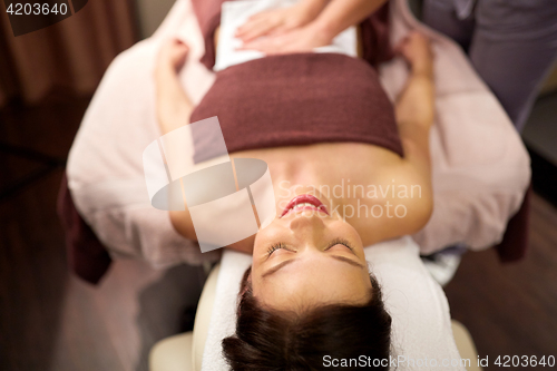 Image of happy young woman lying at spa or massage parlor