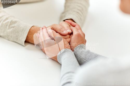 Image of close up of old man and young woman holding hands