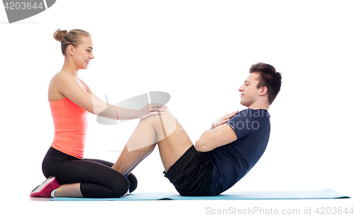 Image of happy sportive man and woman doing sit-ups