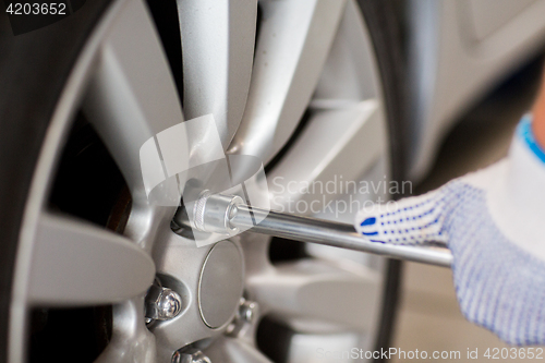 Image of mechanic with screwdriver changing car tire