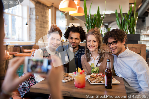 Image of friends with smartphone photographing at cafe