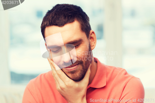 Image of unhappy man suffering toothache at home