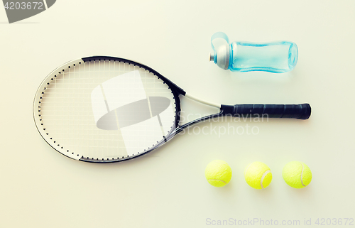 Image of close up of tennis racket with balls and bottle