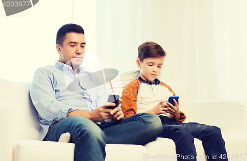 Image of father and son with smartphones at home