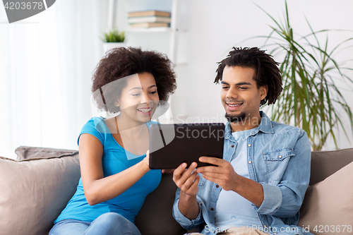 Image of smiling happy couple with tablet pc at home