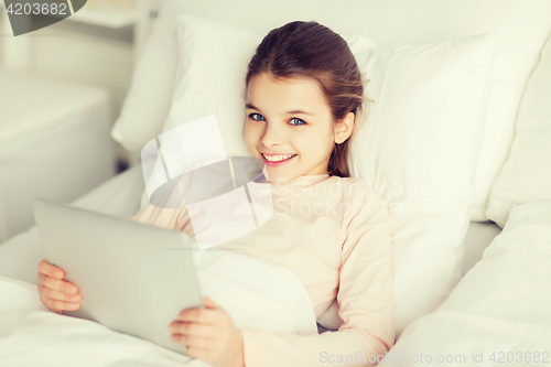 Image of happy girl lying in bed with tablet pc at home