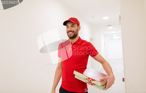 Image of happy delivery man with pizza boxes in corridor