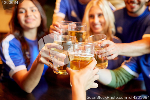 Image of football fans clinking beer glasses at sport bar