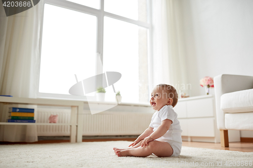 Image of happy baby boy or girl sitting on floor at home