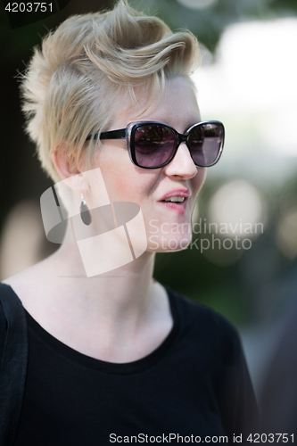 Image of young woman with short blond hair and sunglasses