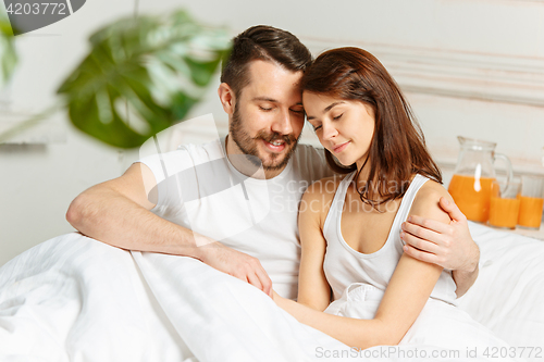 Image of Young adult heterosexual couple lying on bed in bedroom