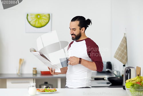 Image of man reading newspaper and eating at home kitchen