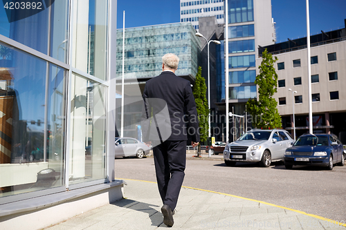 Image of senior businessman walking along city street