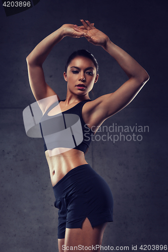 Image of young woman posing and showing muscles in gym