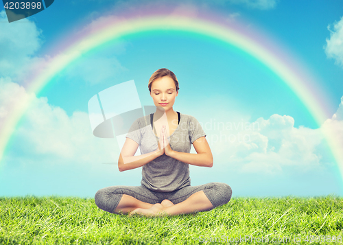 Image of woman meditating in lotus yoga pose over rainbow 