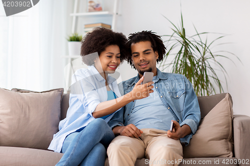 Image of happy couple with smartphones at home