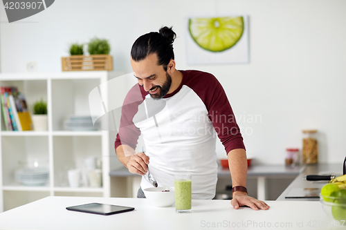 Image of man with tablet pc eating breakfast at home