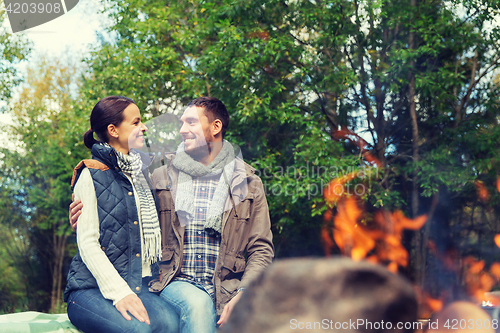 Image of happy couple sitting on bench near camp fire