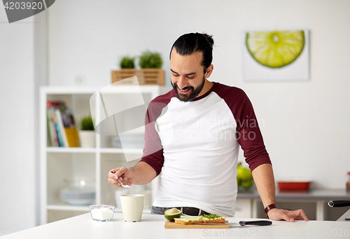 Image of man adding sugar to cup for breakfast at home