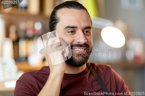 Image of happy man or waiter at bar calling on smartphone