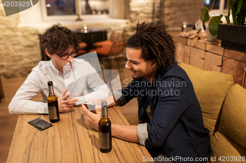 Image of men with smartphones drinking beer at bar or pub