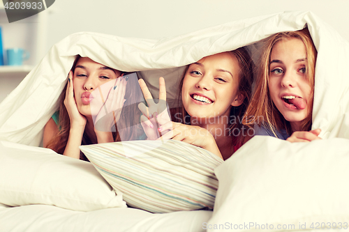 Image of happy young women in bed at home pajama party