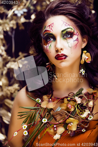 Image of beauty woman with face art and jewelry from flowers orchids clos