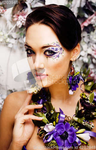 Image of floral face art with anemone in jewelry, sensual young brunette 