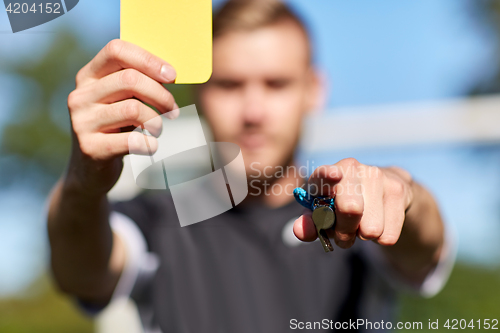 Image of referee on football field showing yellow card